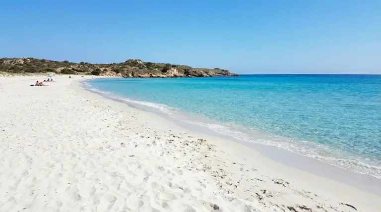 Spiaggia con sabbia bianca e mare turchese in una baia italiana sotto un cielo sereno